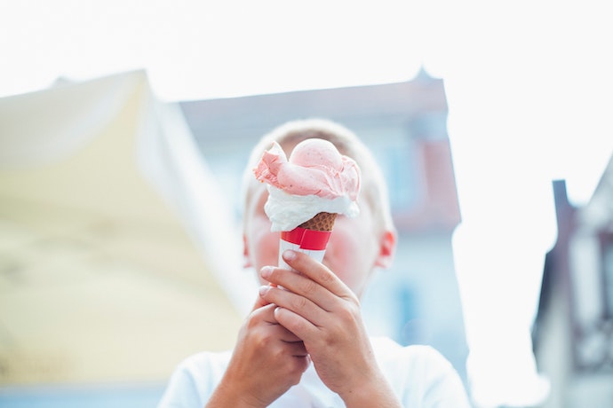 a huge ice cream is in front of a boys face