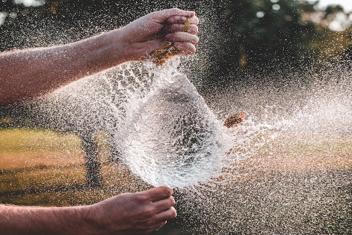 a water ballon explodes in someones hands