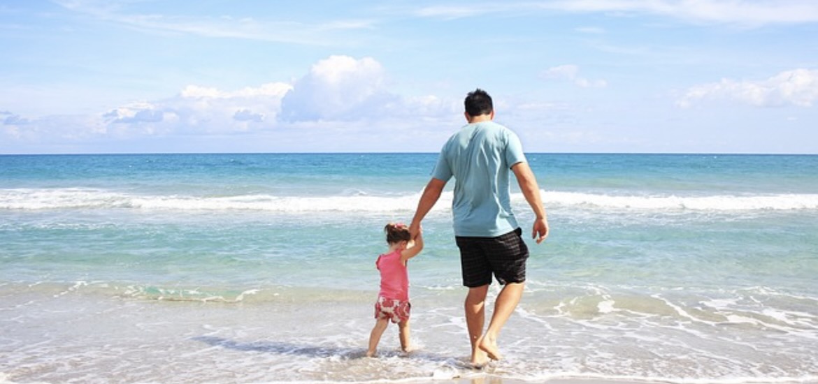 A man walks on the beach with his son