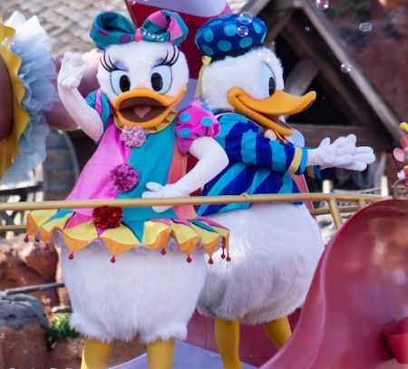 Donald and Daisy duck wave from a float